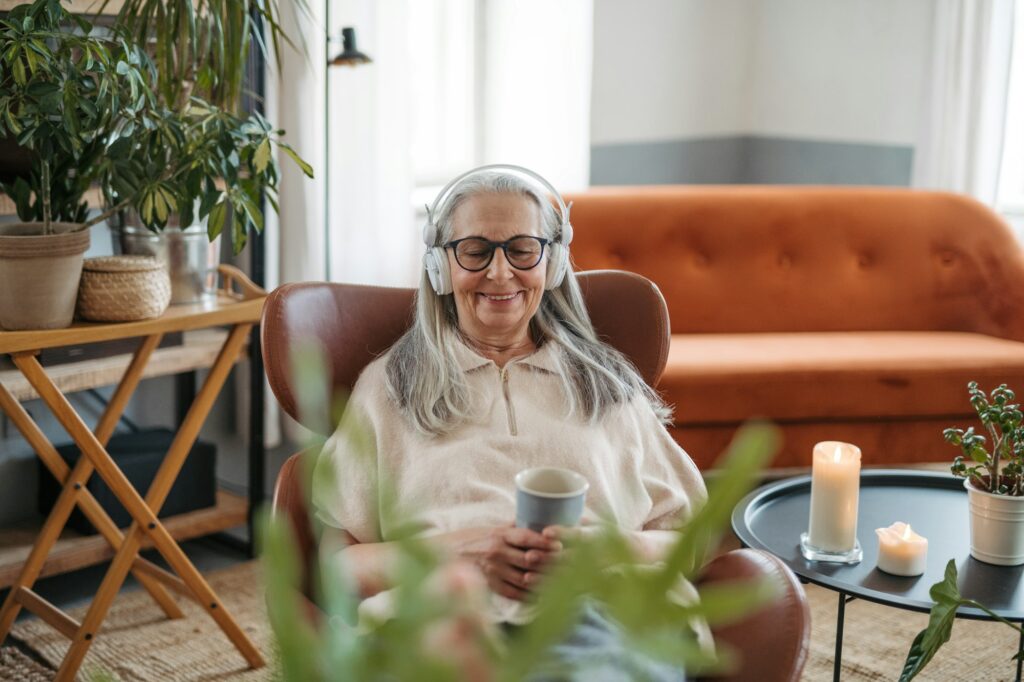 Senior woman resting with cup of tea in her living room, listening music.