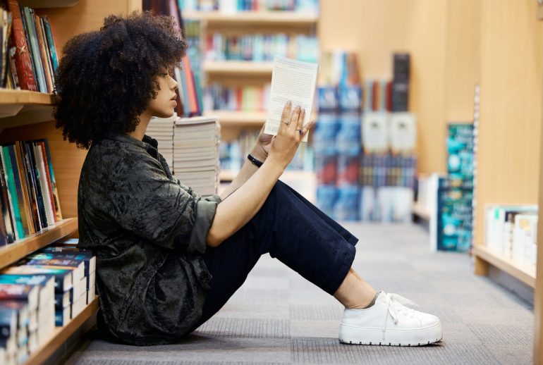 University, library book and girl student learning, reading and studying by school bookshelf for kn